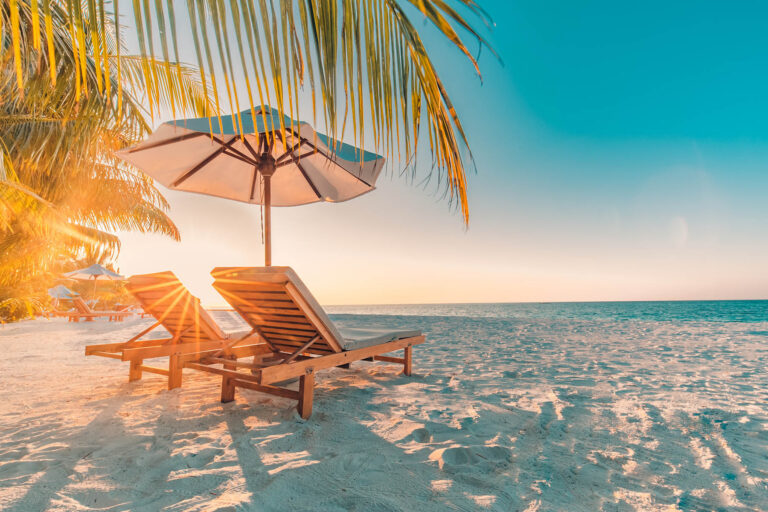 Beach loungers and umbrella at sunset