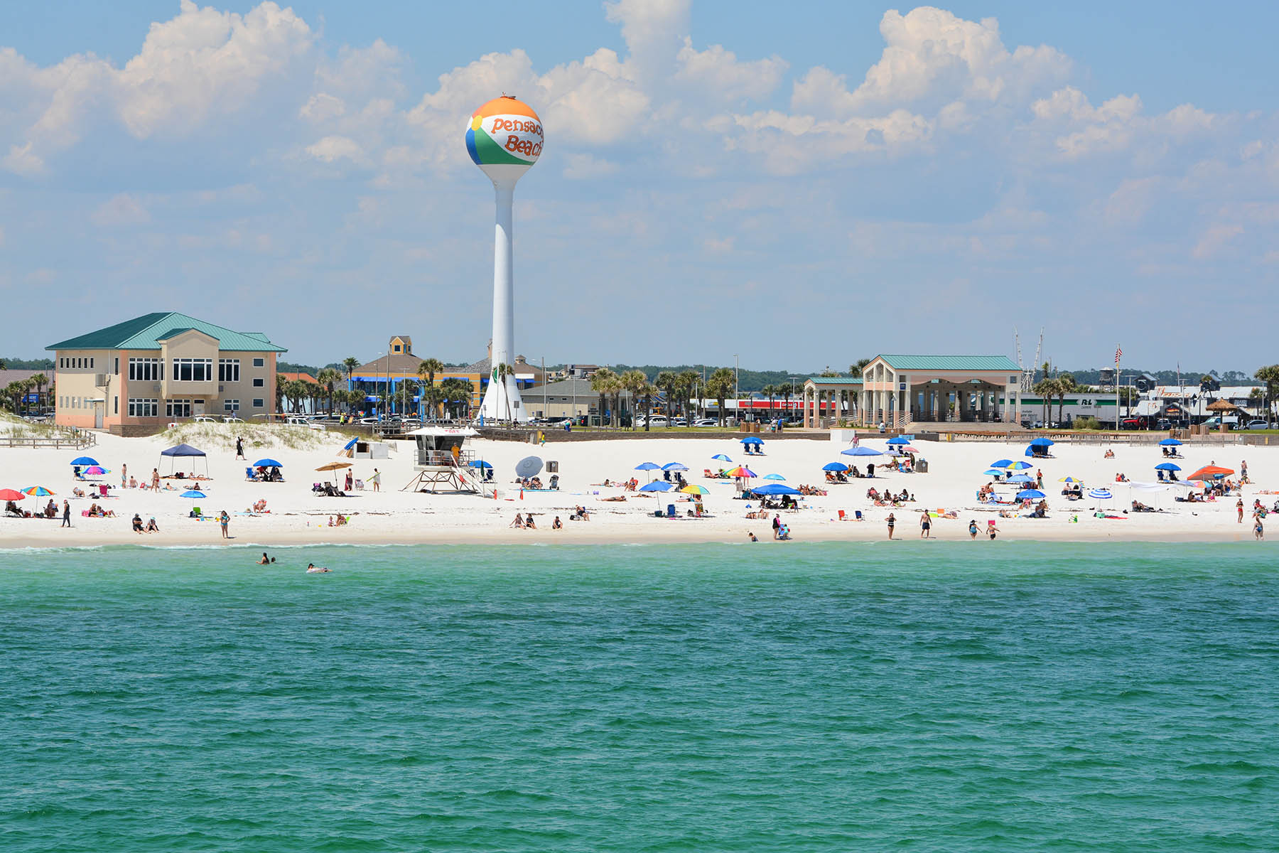 Beachgoers at Pensacola Beach with the beach ball water tower
