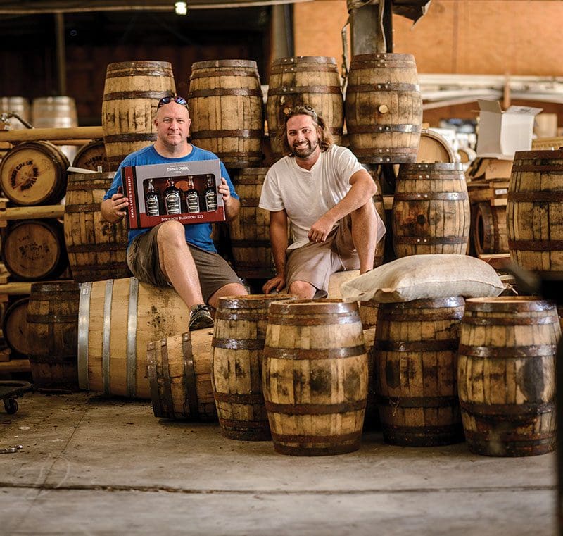 Timber Creek Distillery founders Aaron Barnes and Camden Ford seated on bourbon barrels