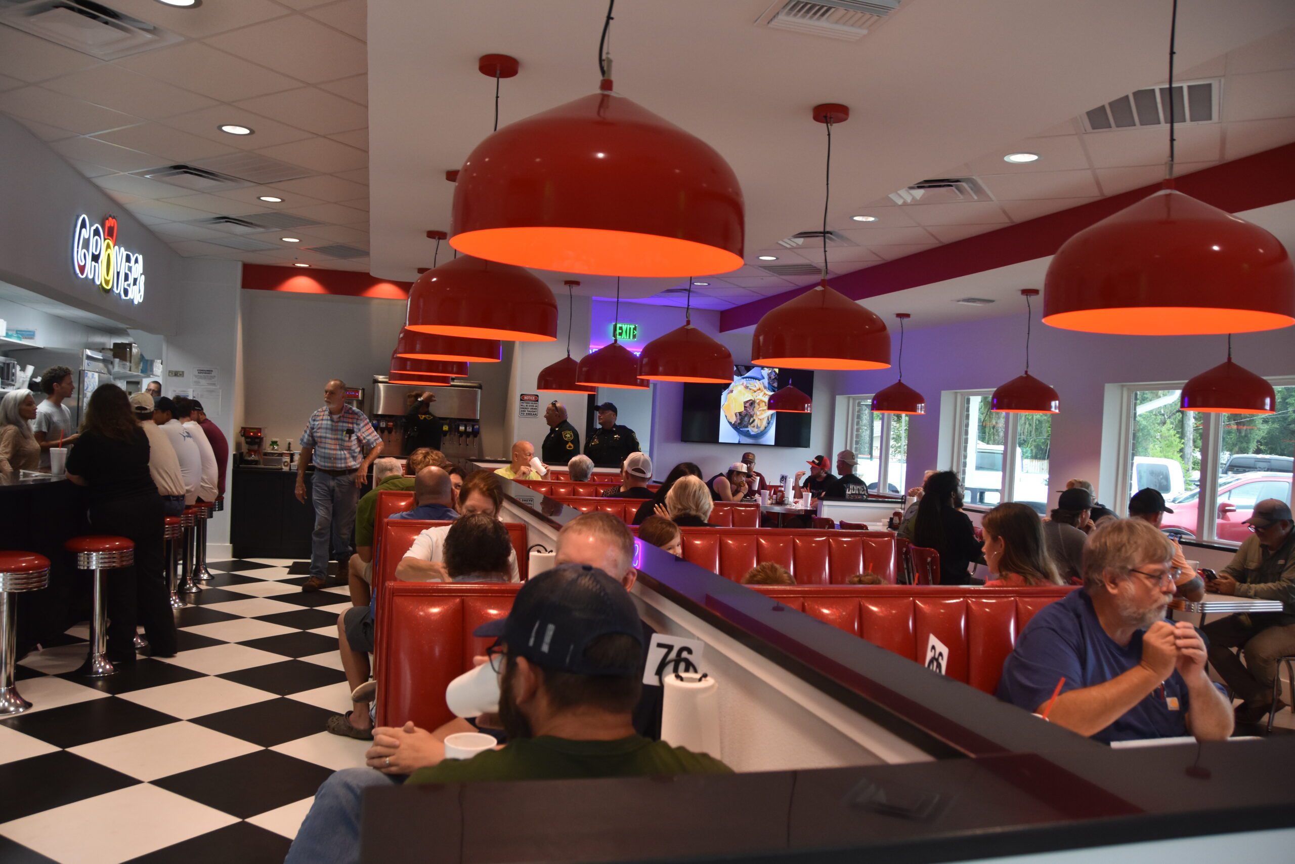 Cherry-red booths filled with customers at the grand opening of Grover's 2.0 in Milton, Florida