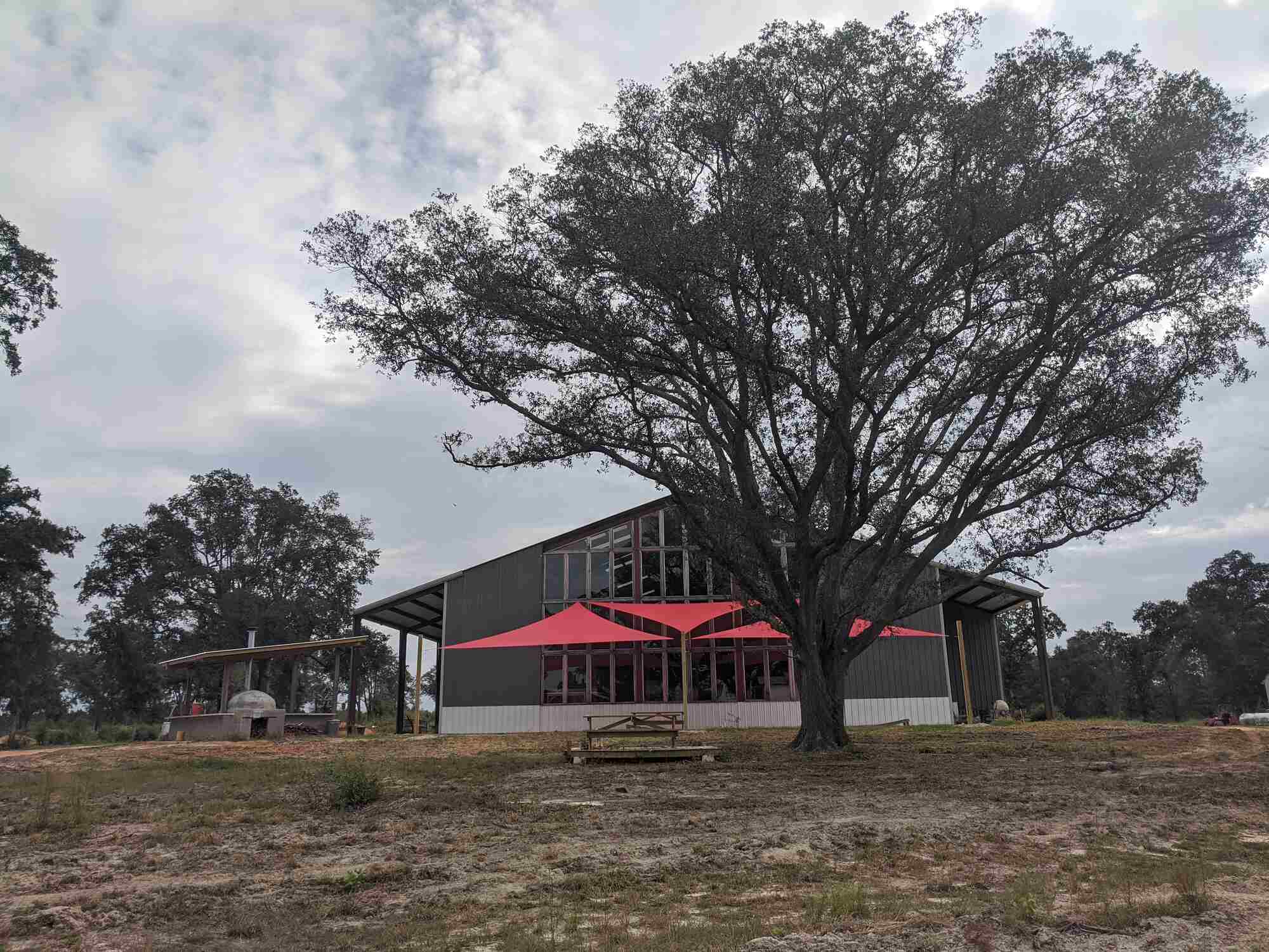 Timber Creek Distillery barn exterior with shade sails under live oak trees in Crestview, Florida