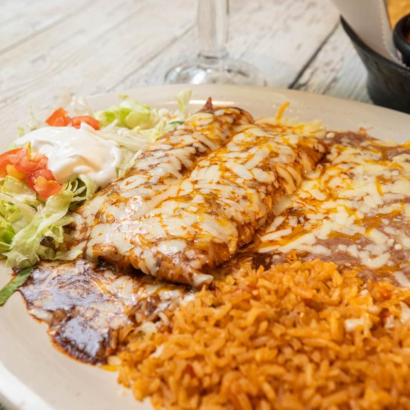 Enchiladas topped with mole sauce and melted cheese at Tacos Rock in Gulf Breeze