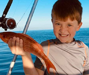 A young angler holding up a fish caught during a Capt. Anderson's Marina charter trip