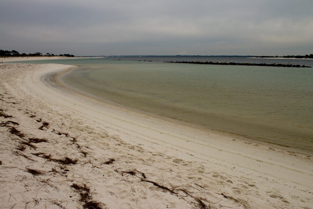 Sandy shoreline curving along the inlet at St. Andrews State Park