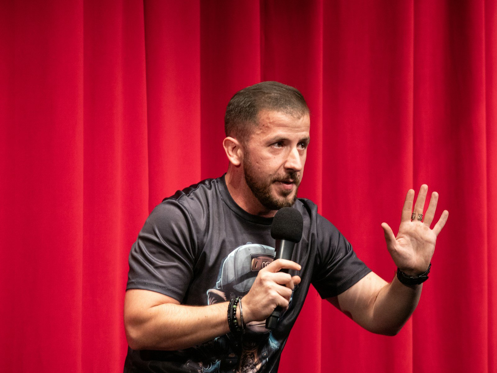 Comedian with a microphone in front of a red curtain