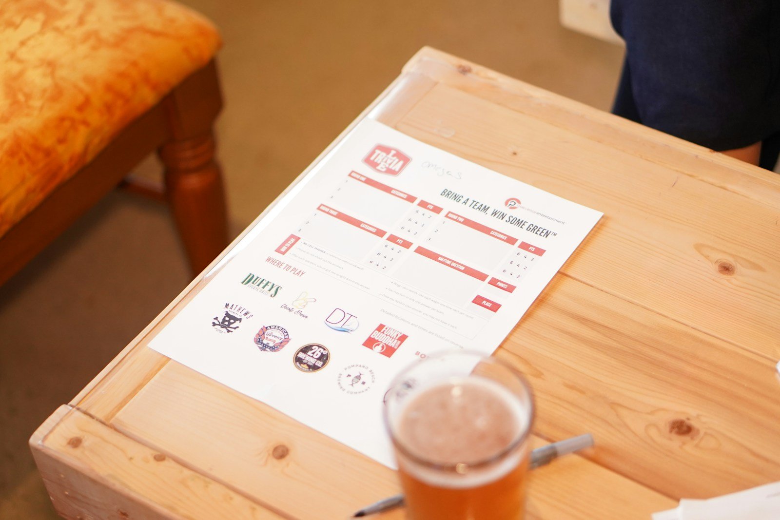 Trivia answer sheet and a beer on a bar table