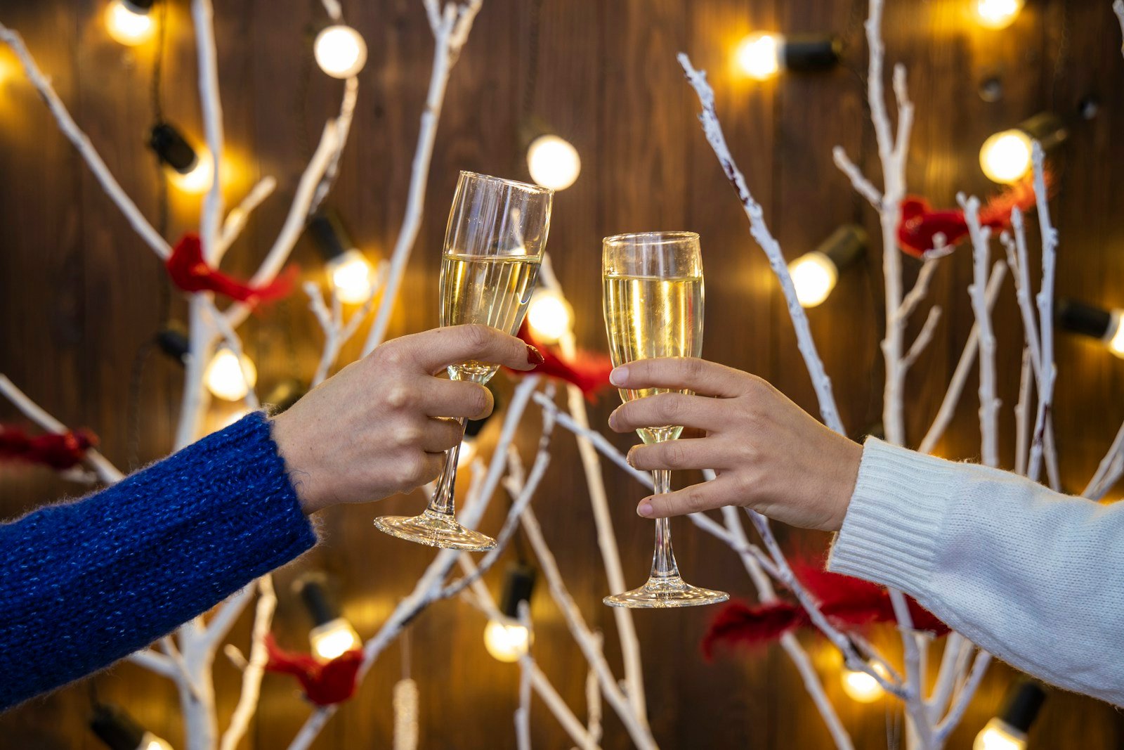Friends toasting with wine glasses in front of holiday lights