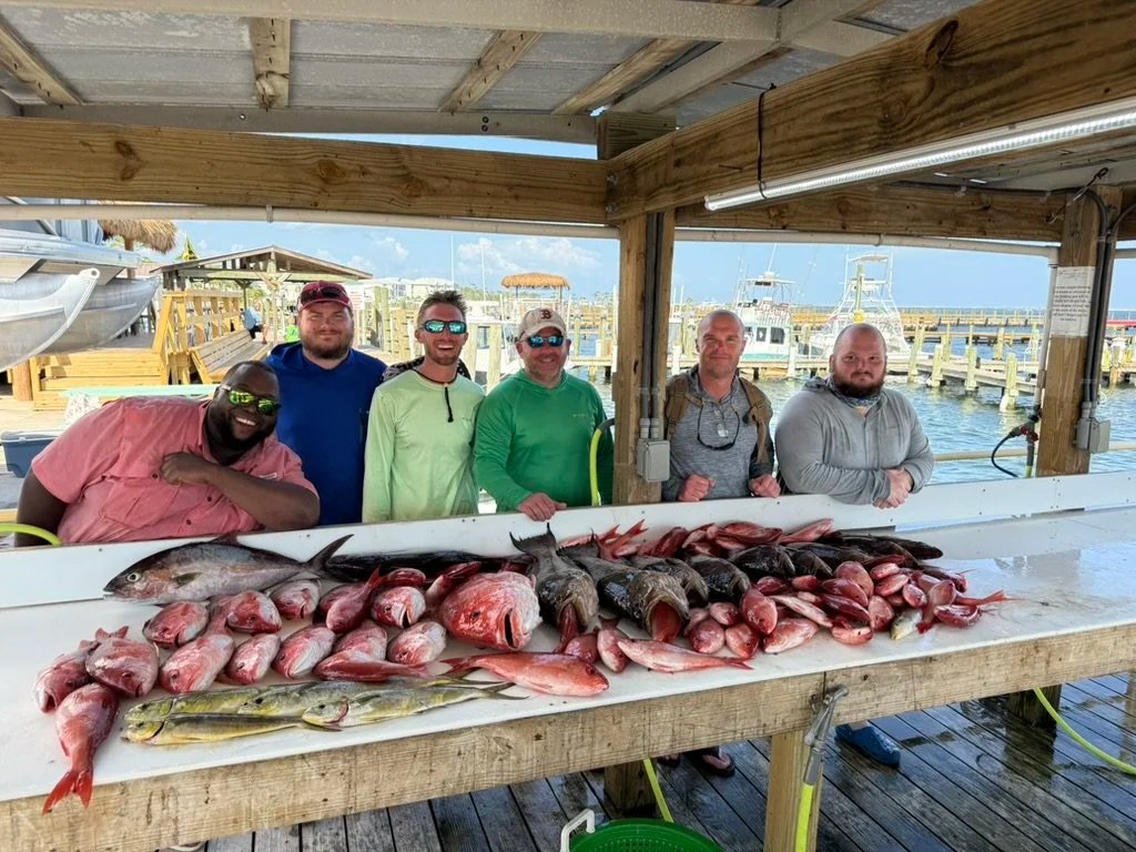 Anglers with a table of red snapper and other offshore catch after a Reel Adventure Charters trip
